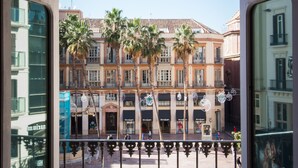 A view from a window with ornate iron railings, overlooking a pedestrian area with palm trees and buildings with balconies. - Holidays2Malaga Comfort Apartments (Málaga)