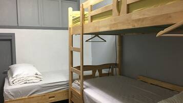 A bunk bed room with two beds, a wooden bunk bed, and a single bed.