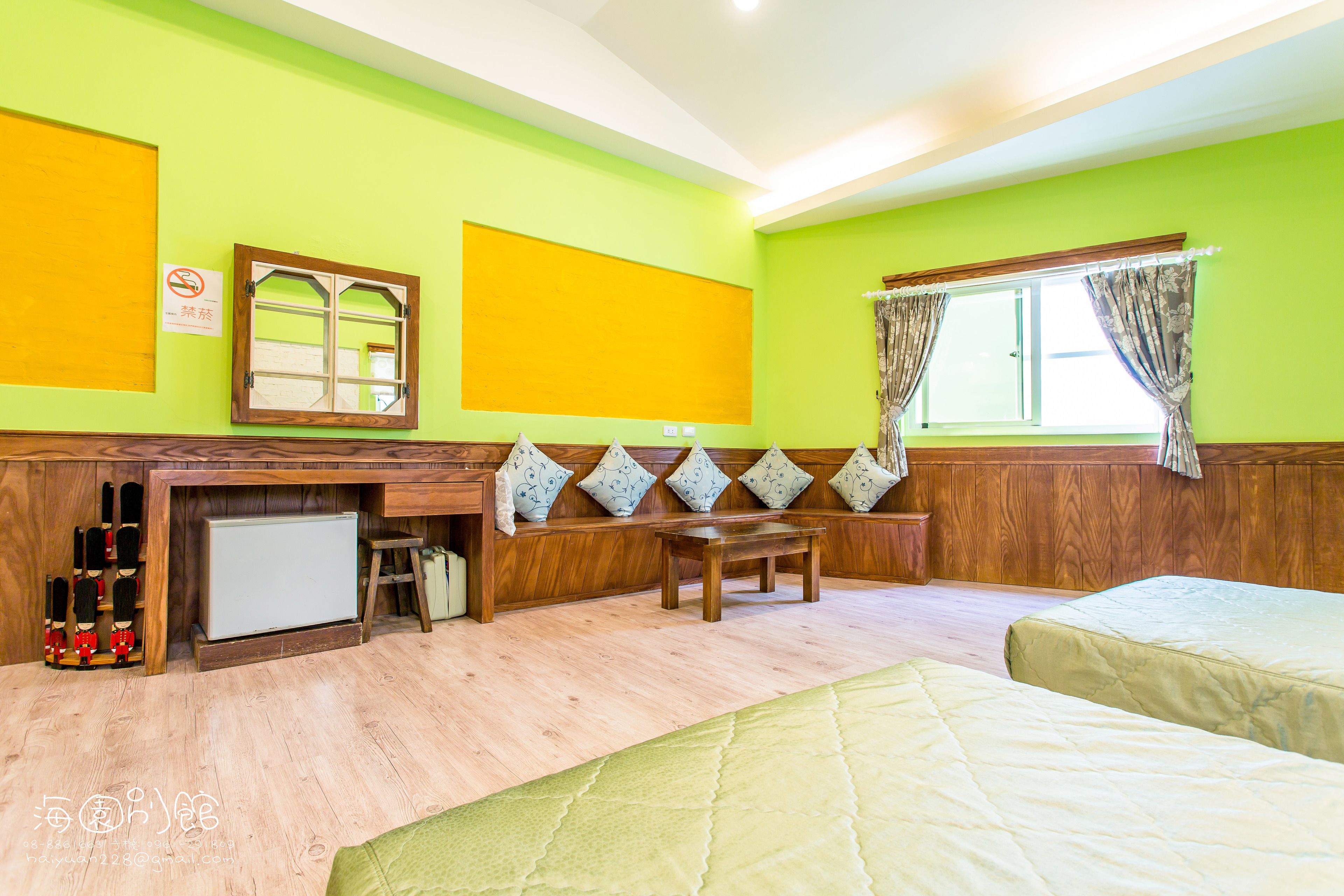 A room with a wooden bench, a small table, and two beds.