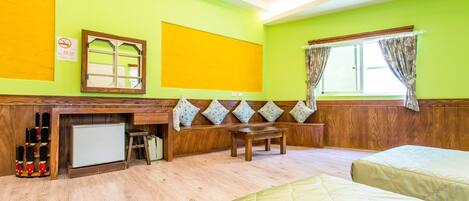 A room with a wooden bench, a small table, and two beds.