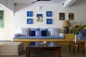 A living room with a striped sofa, a coffee table, and a lamp. - Villa Nilaya (Koggala)