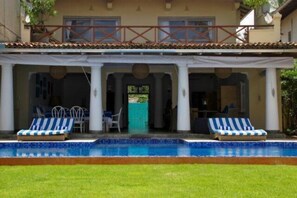 A two-story building with a covered outdoor area featuring a swimming pool, lounge chairs, and a dining area. - Villa Nilaya (Koggala)