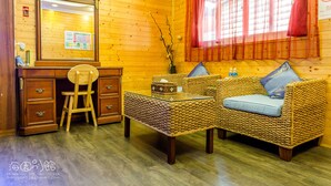 A wooden interior with a sofa, a glass coffee table, a wooden desk with drawers, and a chair. - Hai Yuan Hotel 2 (Hengchun)