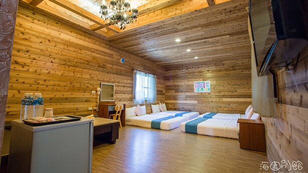 A wooden cabin with a chandelier, a desk, two beds, and a refrigerator. - Hai Yuan Hotel 2 (Hengchun)