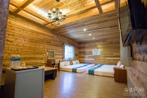 A wooden cabin with a chandelier, a desk, two beds, and a refrigerator. - Hai Yuan Hotel 2 (Hengchun)