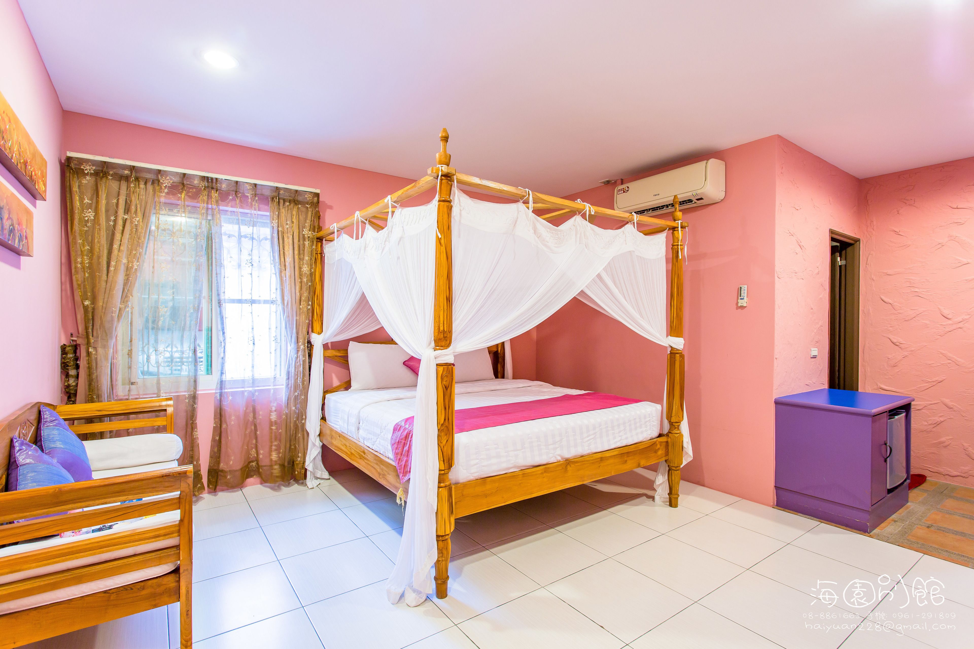 Quarto com cama de dossel, um banco de madeira, um pequeno armário roxo e uma janela com cortinas leves.