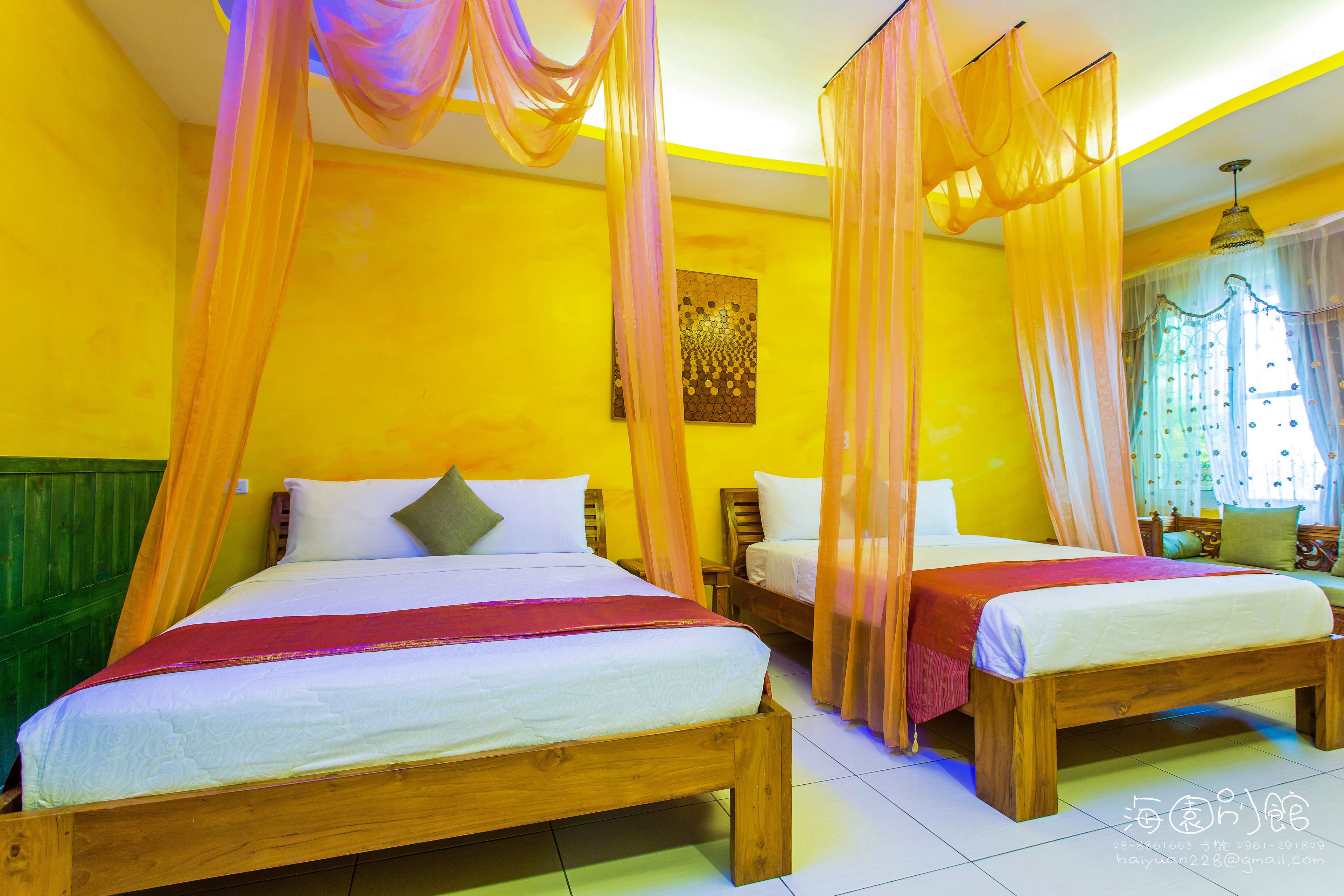 A room with two wooden beds, each with a canopy, and a window with curtains.