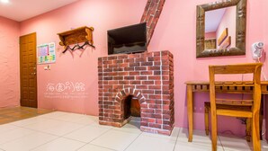 A room with a brick fireplace, a wooden TV shelf, a wooden table, and a mirror on the wall. - Hai Yuan Hotel 2 (Hengchun)
