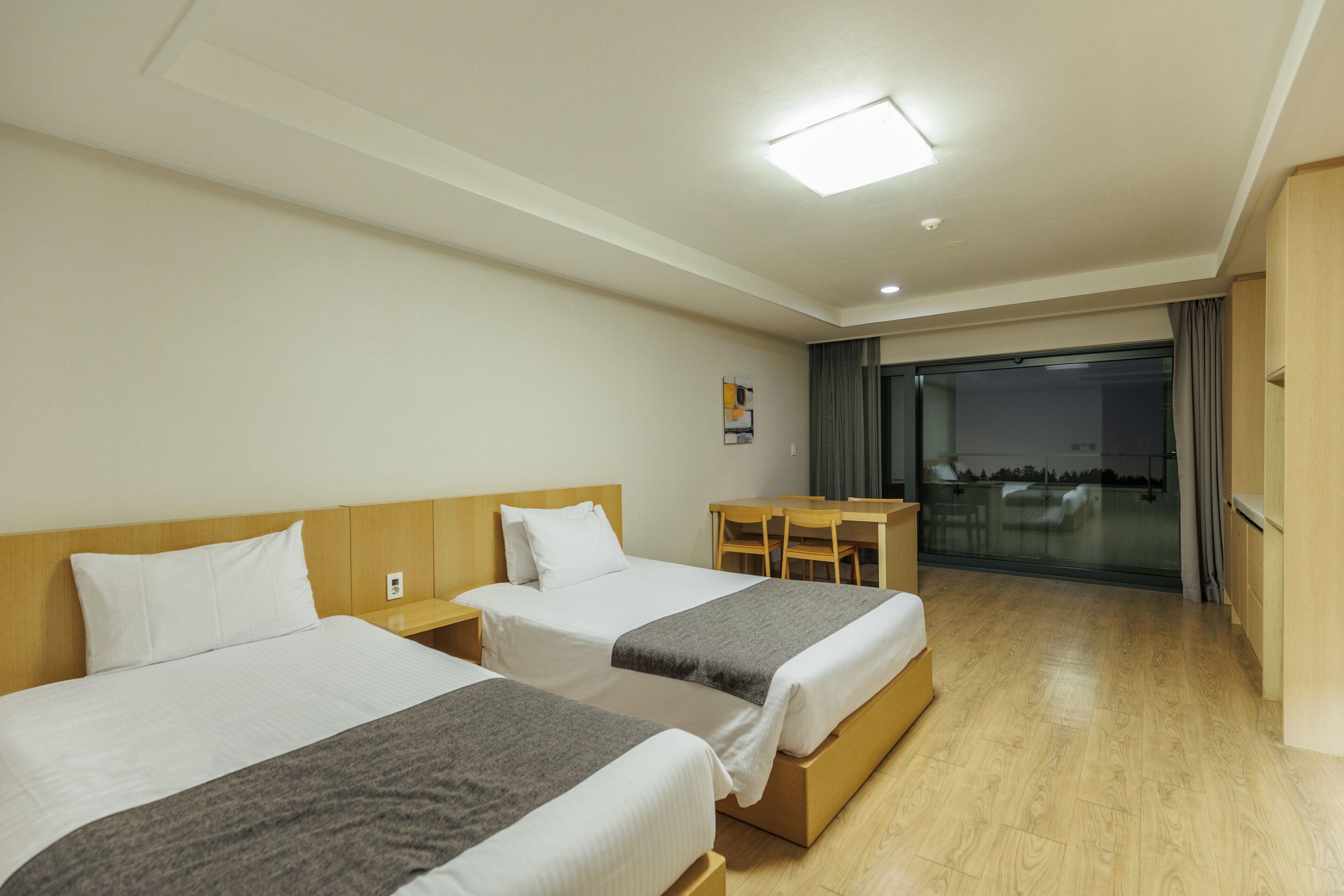 Quarto de hotel com duas camas, uma escrivaninha e vista para o exterior.