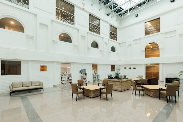 A spacious lobby with a high ceiling, multiple seating areas, and a central plant. - Luceville (Seogwipo)