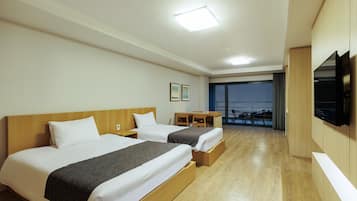 Ein Hotelzimmer mit zwei Betten, einem Schreibtisch und einem Fernseher.