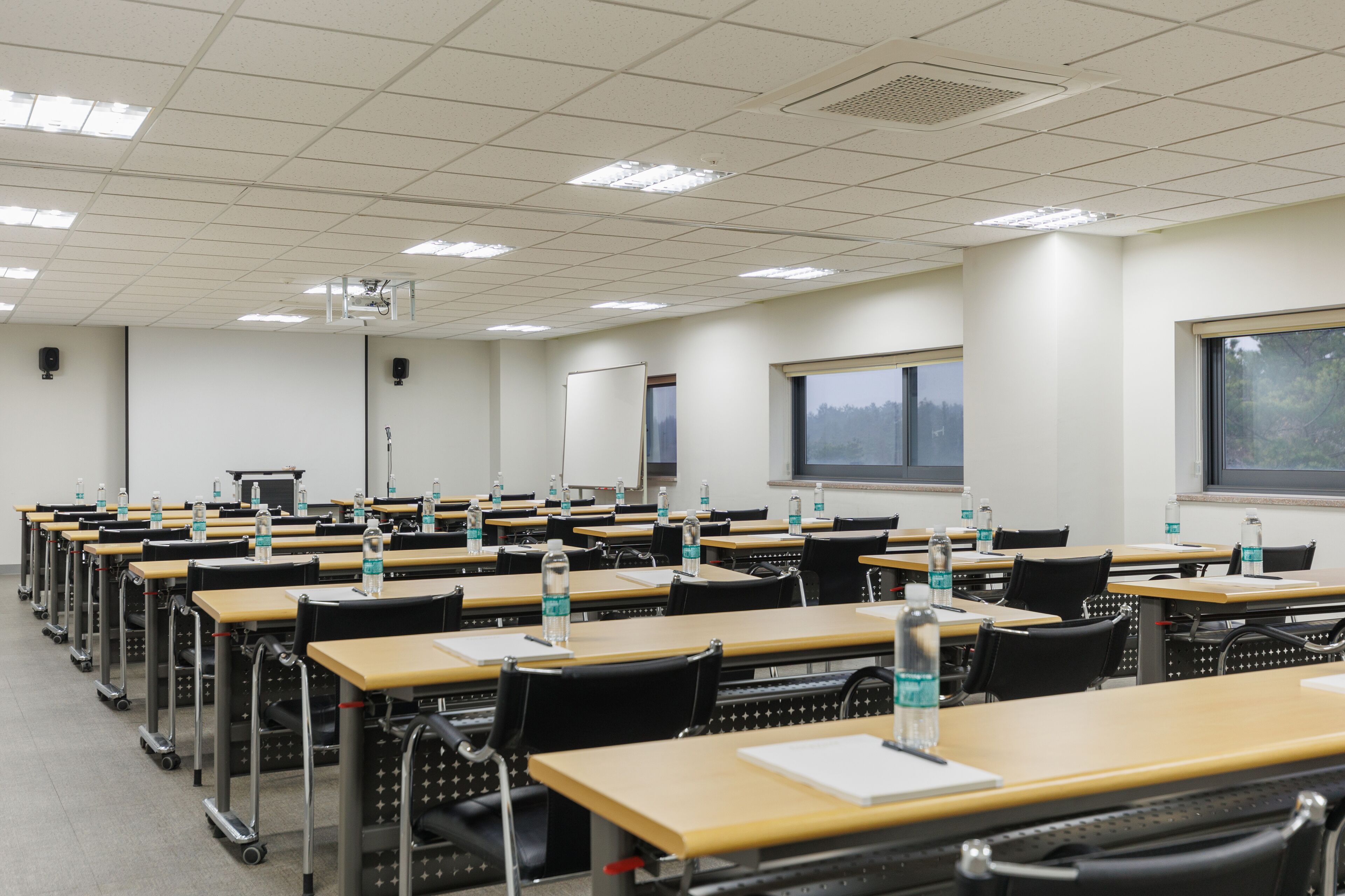 A classroom with rows of desks, chairs, and water bottles.