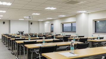 A classroom with rows of desks, chairs, and water bottles.