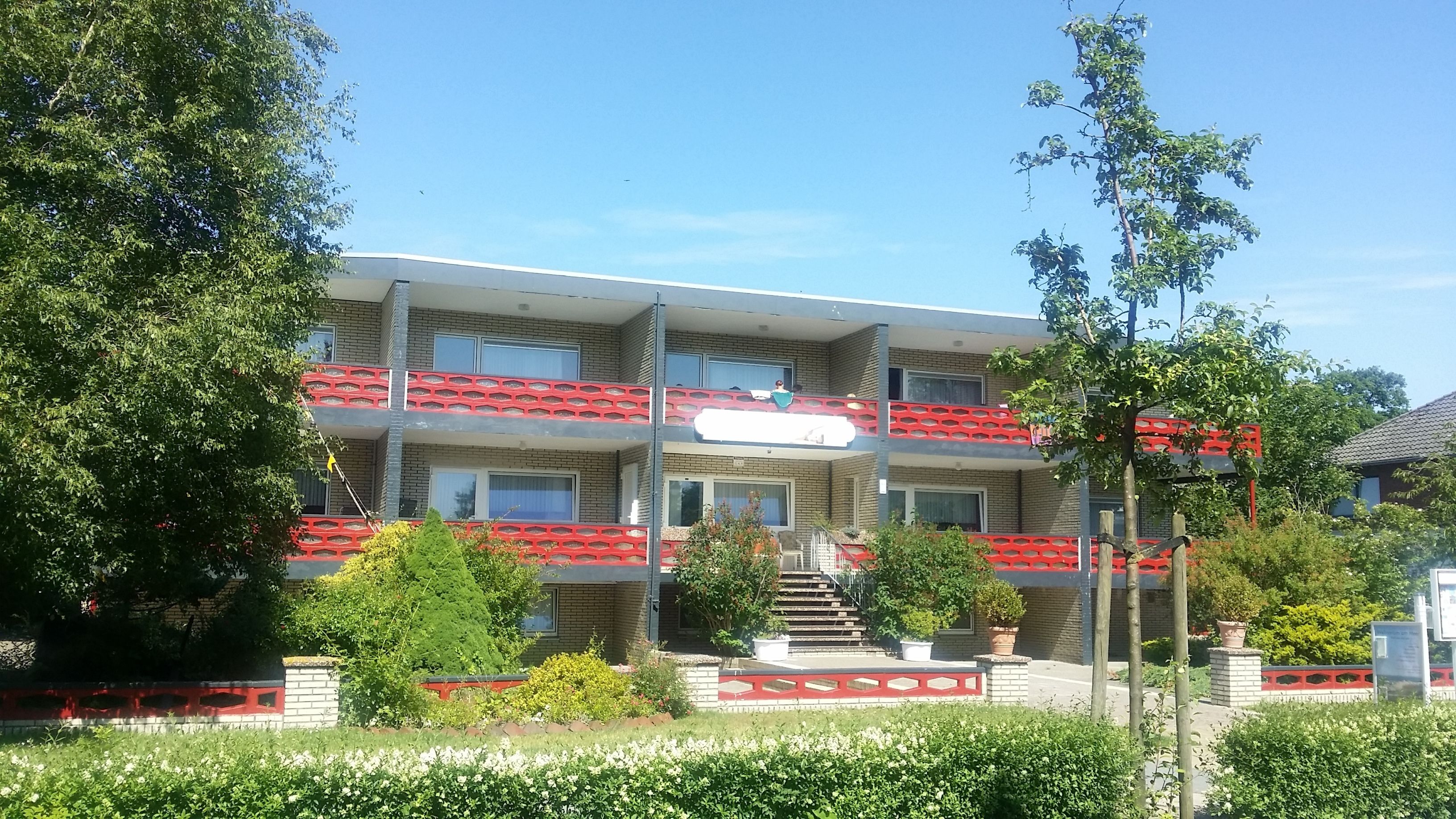 Um edifício com vários andares, varandas, escadaria e área de jardim.