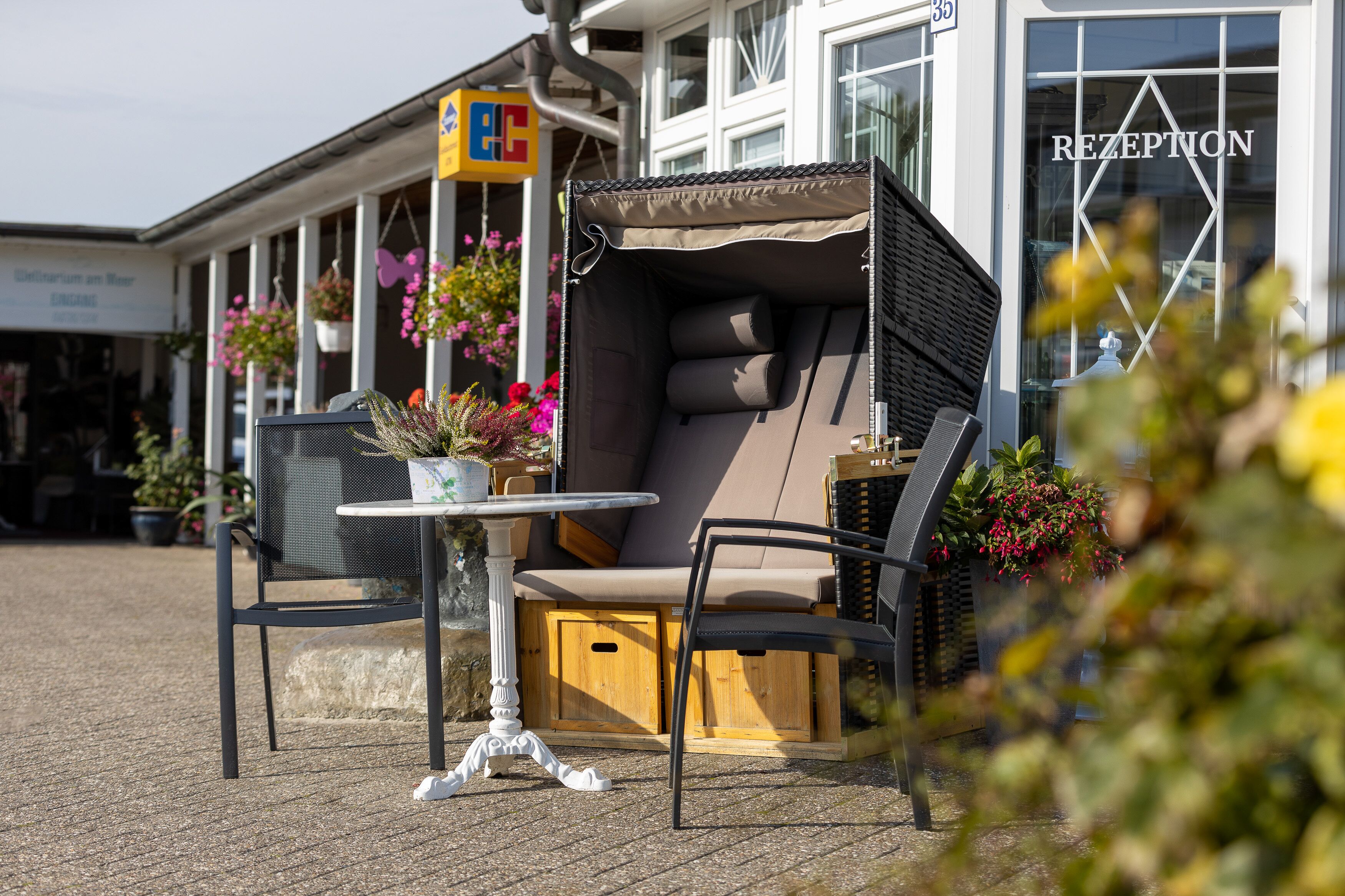 An outdoor seating area with a table and chairs, a cushioned bench, and potted plants.