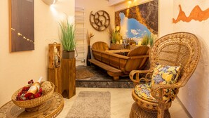 A cozy room with a wicker chair, a wooden bench, and a decorative wall. - Familien- & Aparthotel Strandhof (Butjadingen)