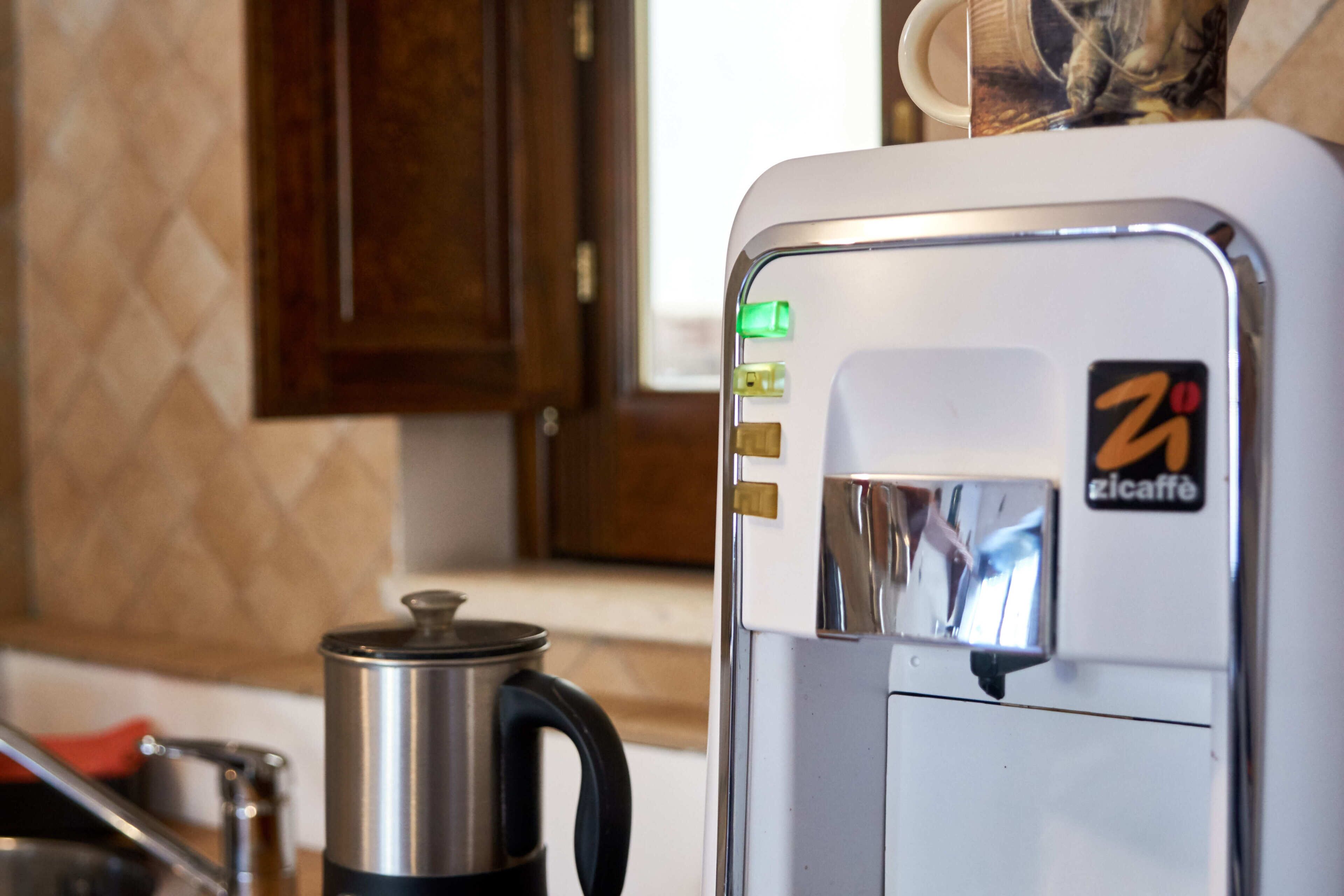 Una macchina per caffè con un logo, un bollitore e un armadietto sullo sfondo.