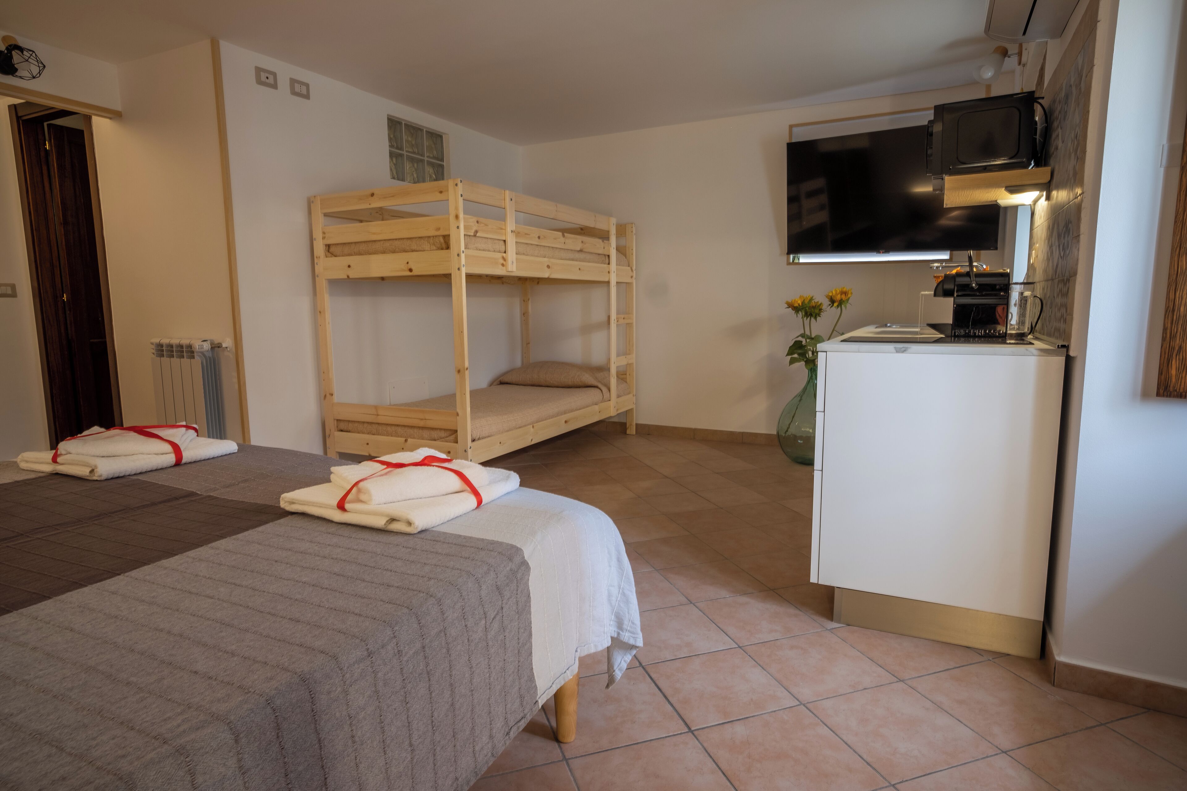 Une chambre avec deux lits, une kitchenette et un téléviseur.