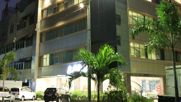 A multi-story hotel with a prominent 'HOTEL 55' sign, street lighting, and a parking area with cars. - Hotel 55 (Jakarta)