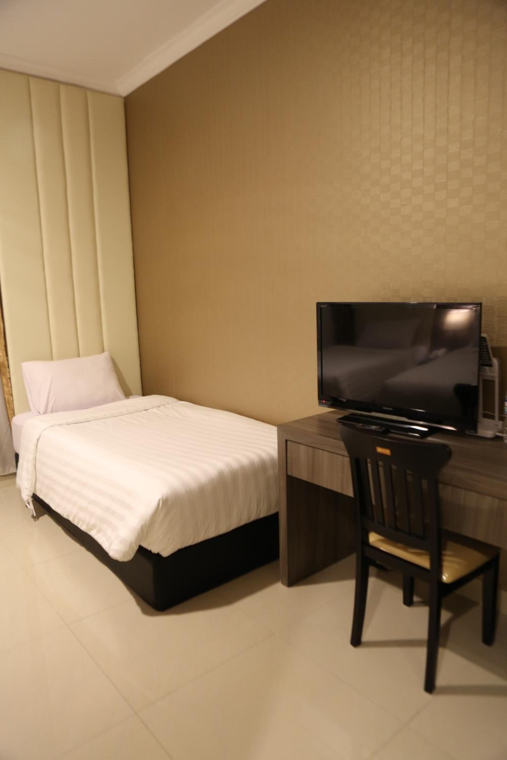 Ein Hotelzimmer mit einem Bett, einem Schreibtisch mit Fernseher und einem Sessel.
