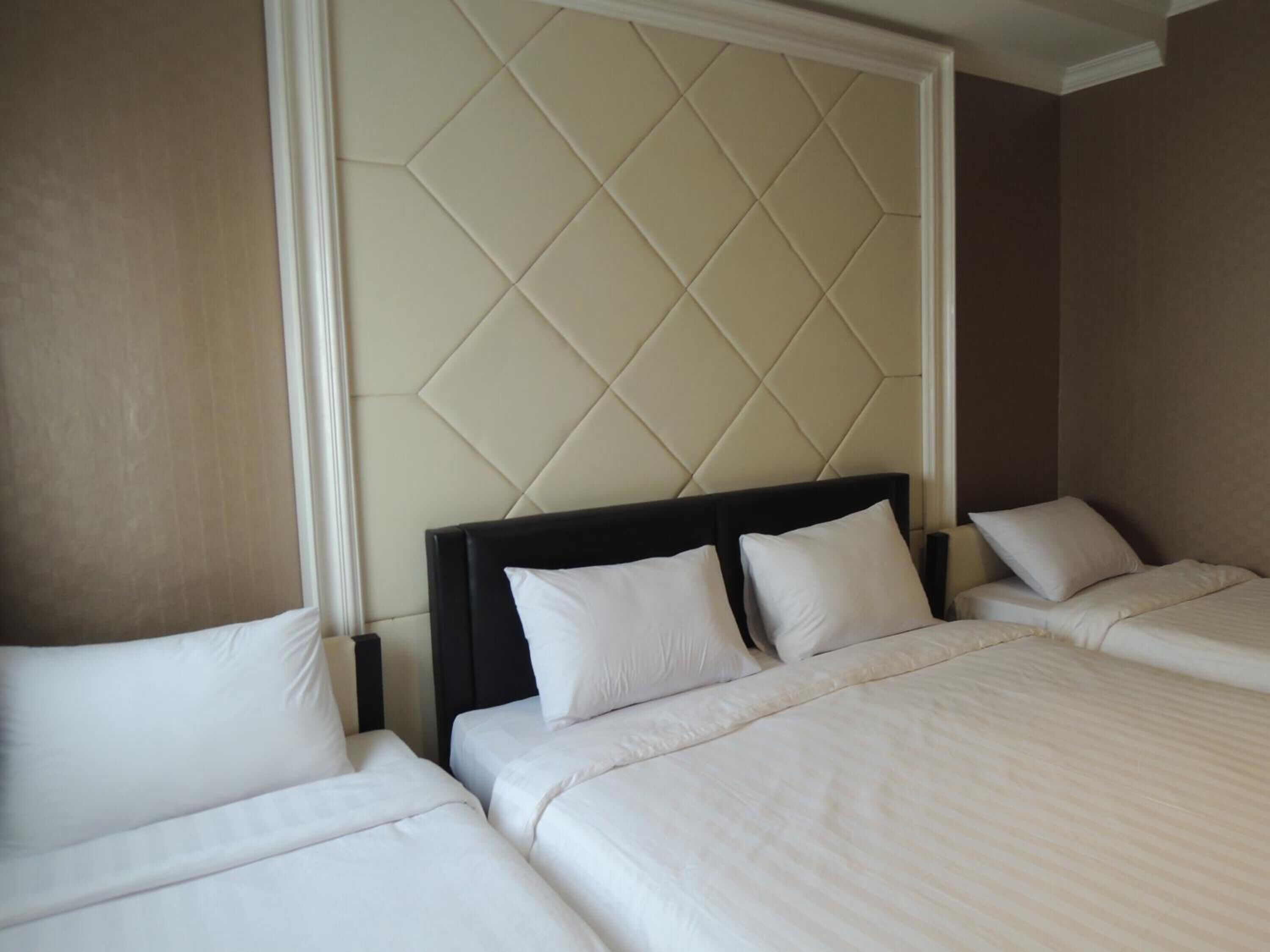 A hotel room with two beds, a padded headboard, and a large window.