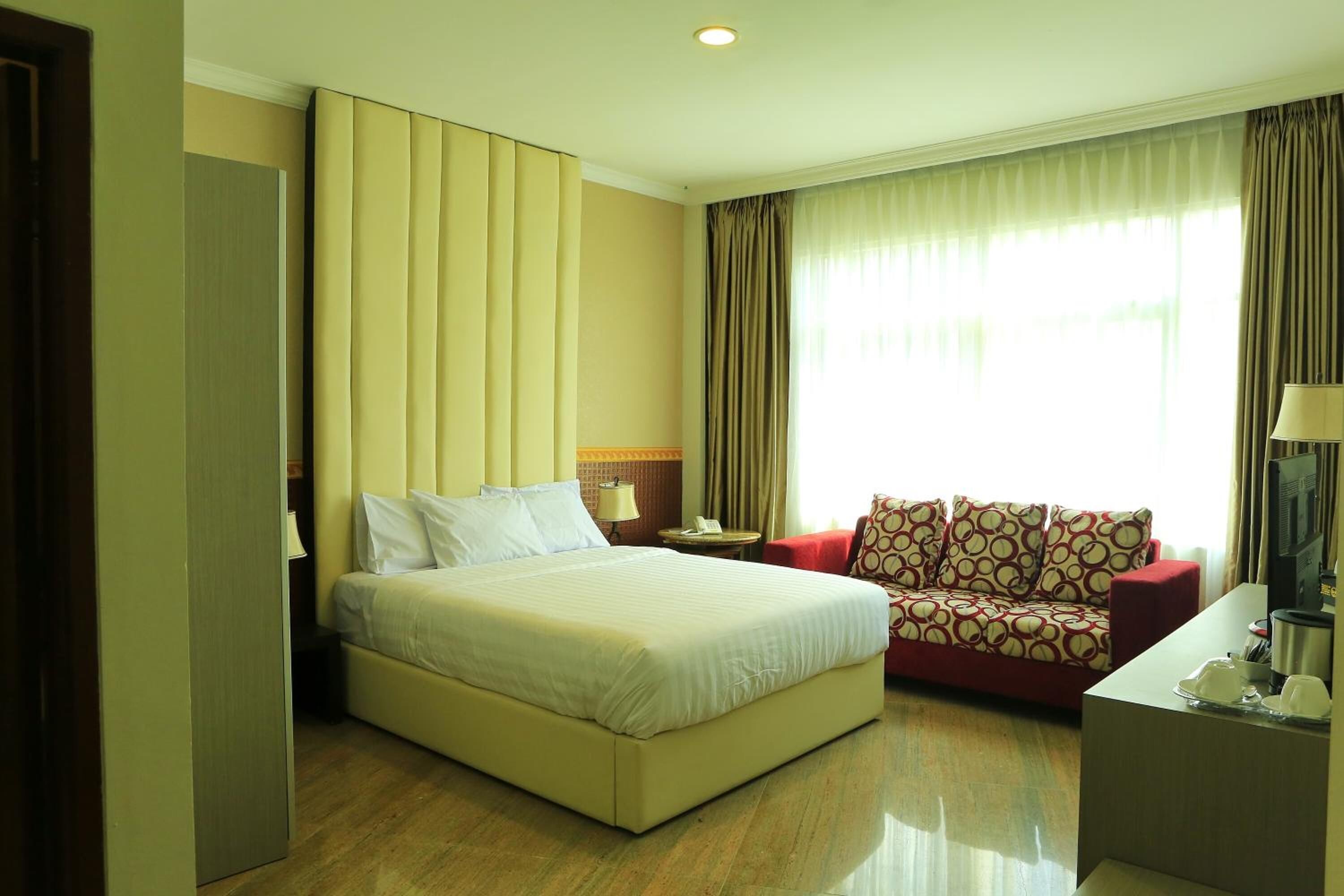 A hotel room with a bed, a sofa, a desk, and a TV.