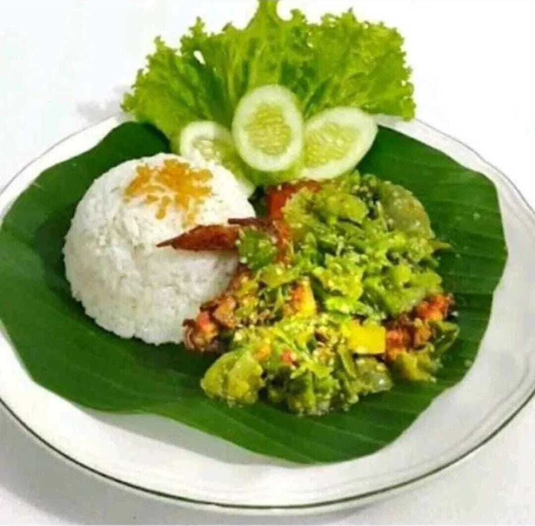 Un plato de comida con arroz, una ensalada de verduras y un huevo frito sobre una hoja de plátano.