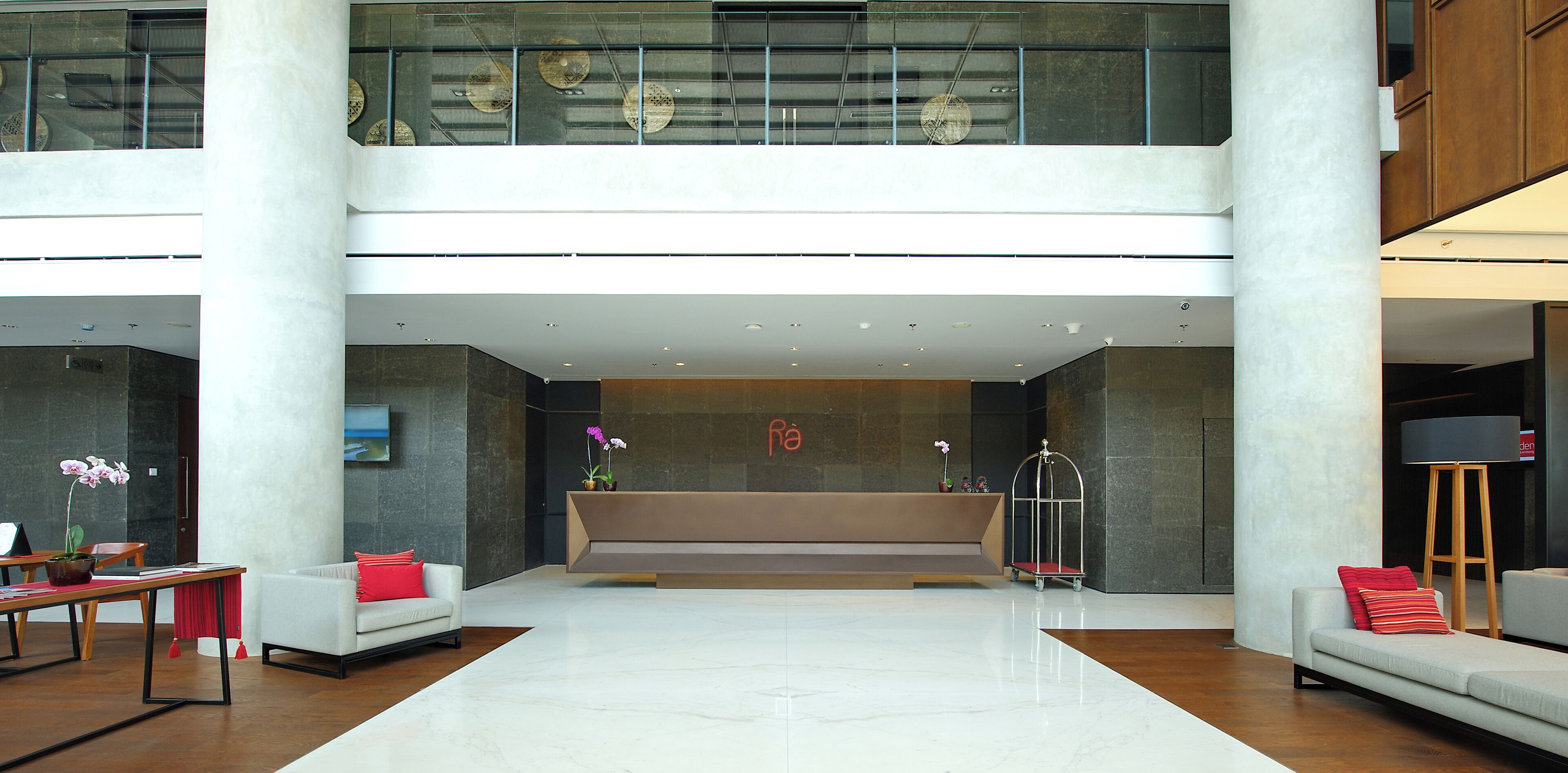 A spacious lobby with a reception desk, seating area, and a high ceiling with decorative elements.