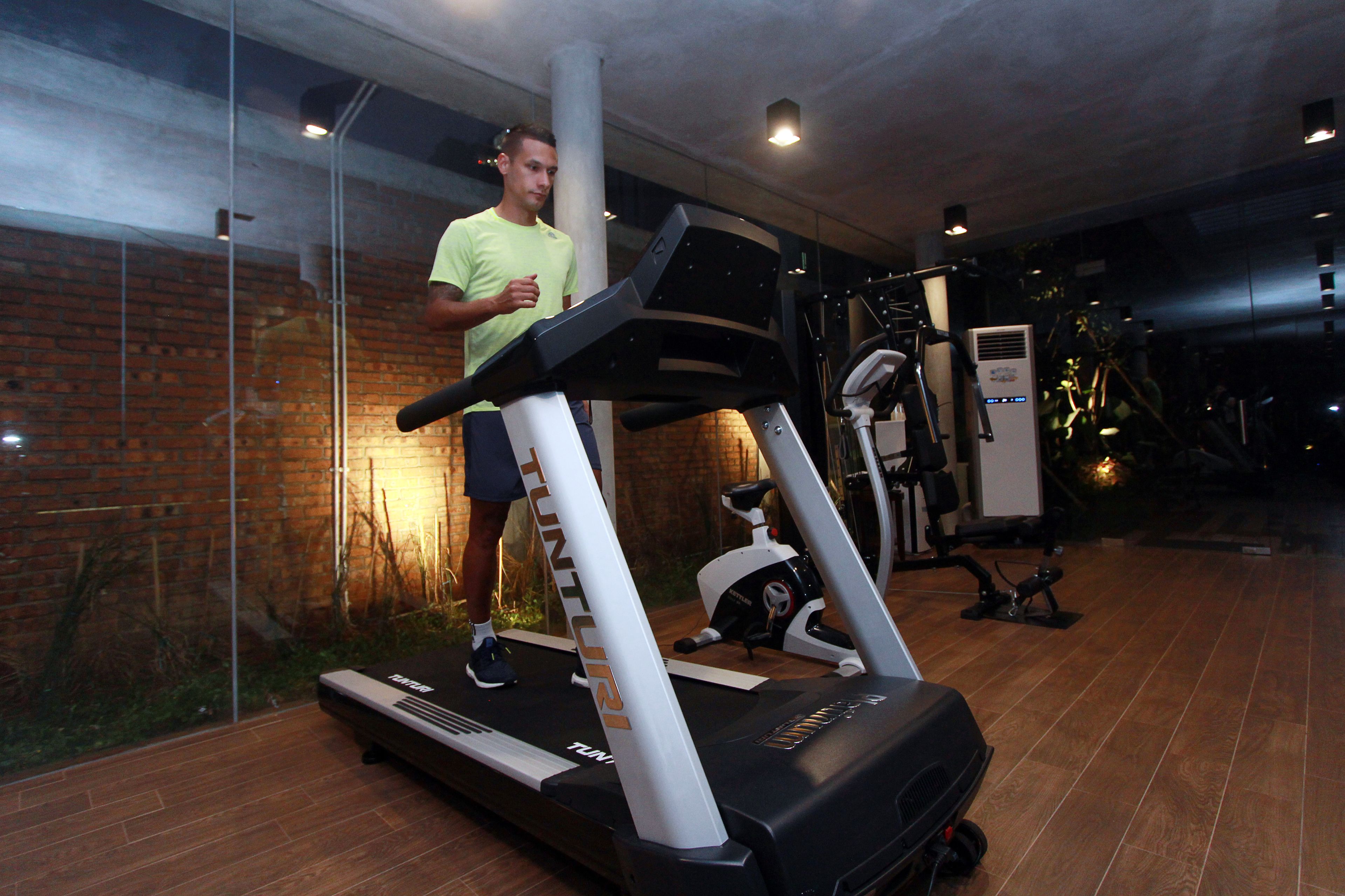 Ein Fitnessraum mit Laufband, Ergometer und einer Ziegelwand.