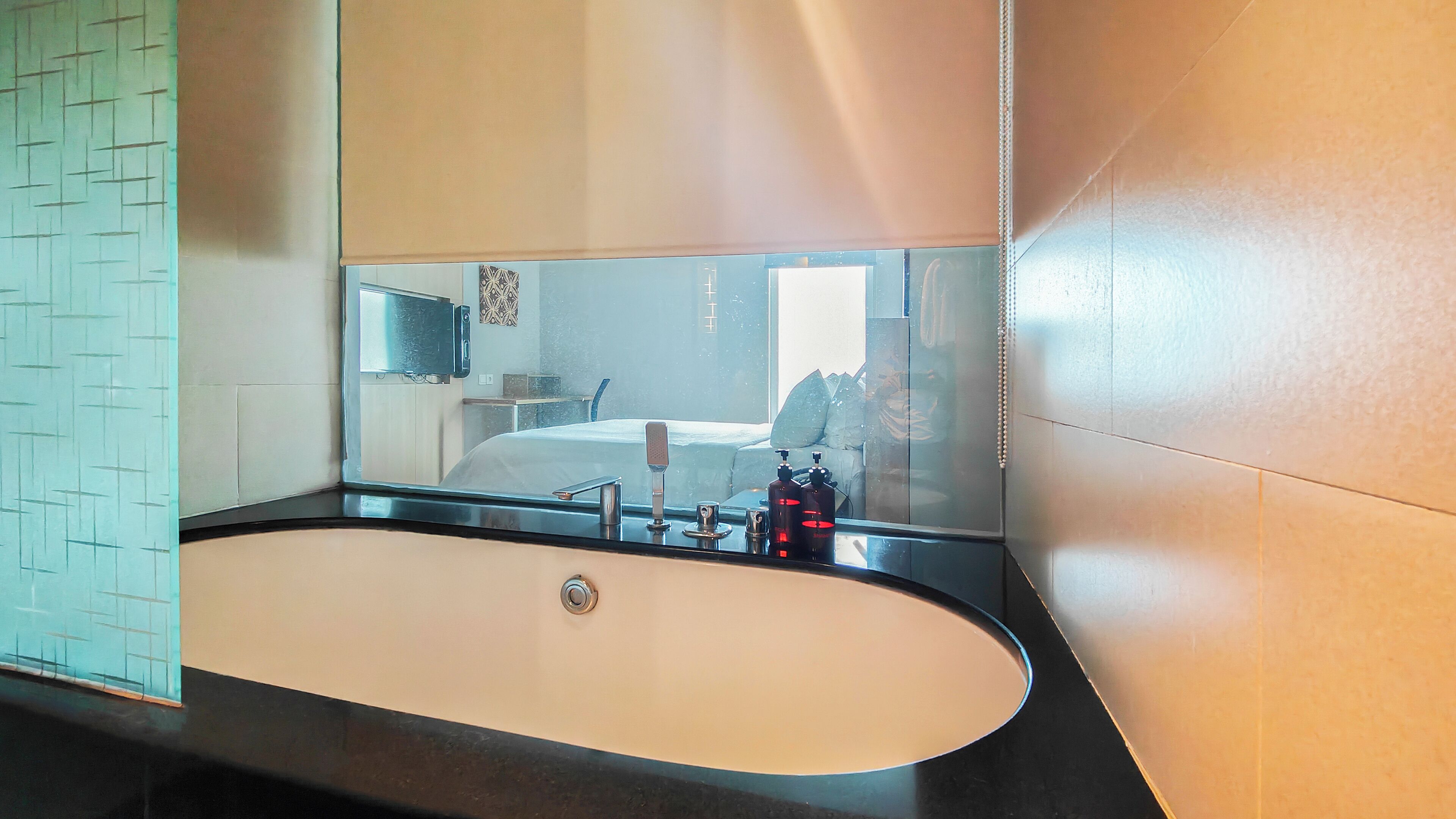 A modern bathroom with a large oval sink, a mirror, and a wall-mounted TV.