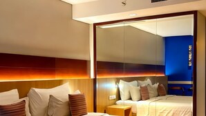Una habitación de hotel con dos camas, un espejo grande y un diseño moderno.
