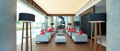 A spacious lobby with modern seating, large windows, and a central table.