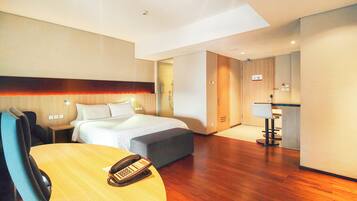 Habitación de hotel con cama, escritorio con teléfono, silla, mesita y espejo.