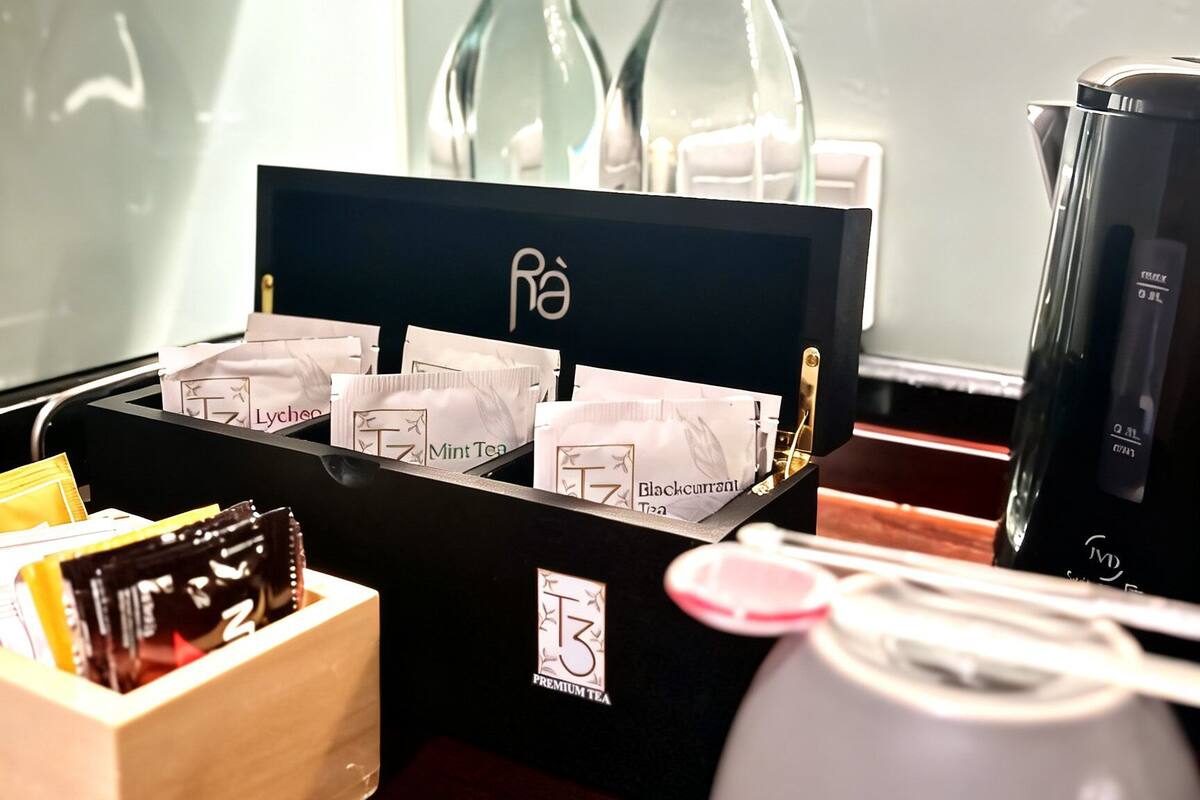 A tea station with a black box containing tea packets, a kettle, and a coffee maker.