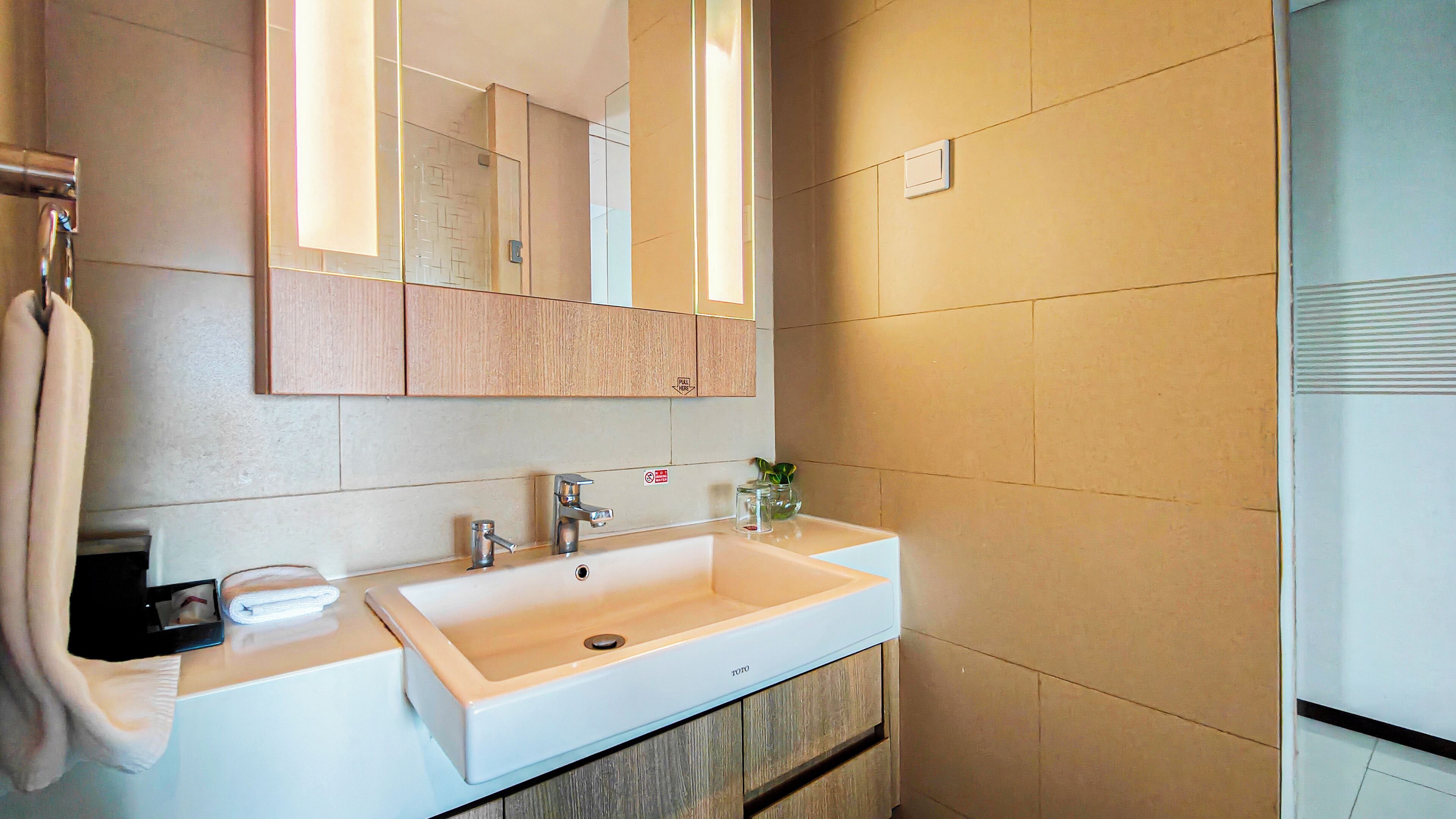 Un baño con un lavamanos blanco, un espejo y armarios de madera.