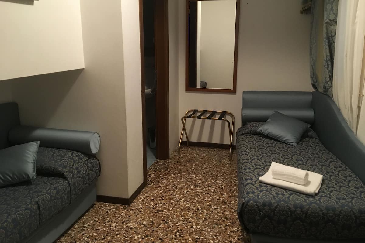 A room with two sofas, a mirror, and a small table with a towel.