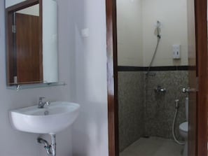 A bathroom with a white sink, a mirror, and a shower area. - Twin Star (Surakarta)