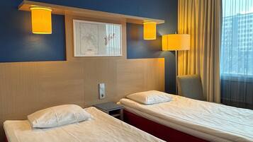 A hotel room with two single beds, a wooden headboard, a framed map, and a window with curtains.