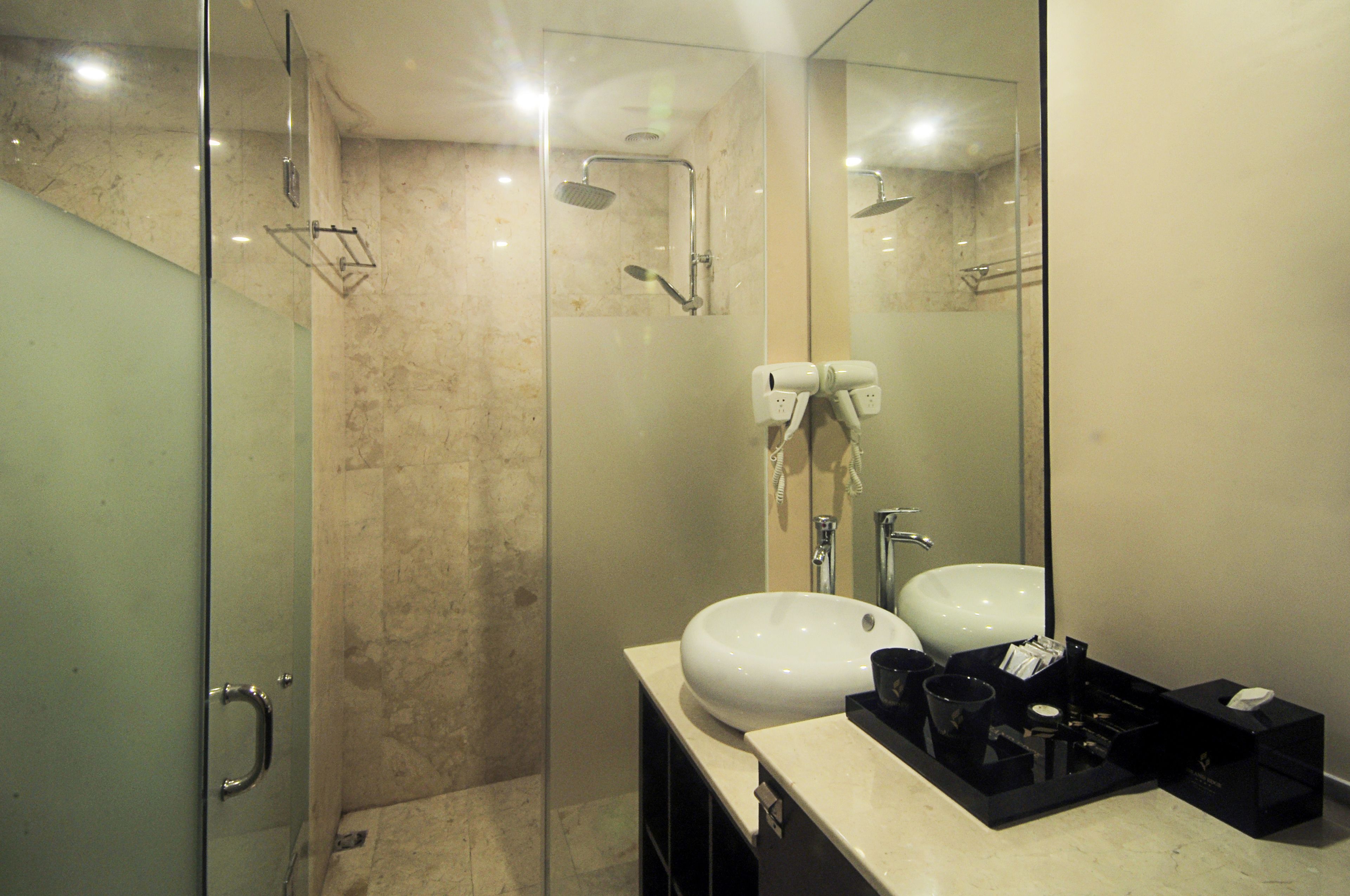 A modern bathroom with a glass-enclosed shower, a white sink, and a vanity with toiletries.