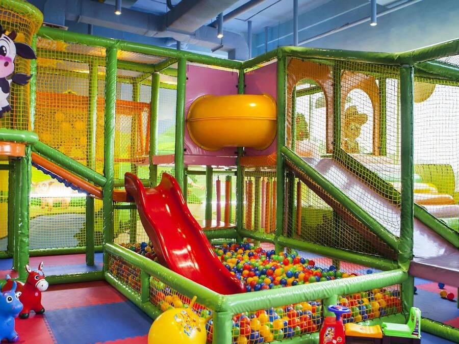 A children's play area with a slide, ball pit, and netted play structures.