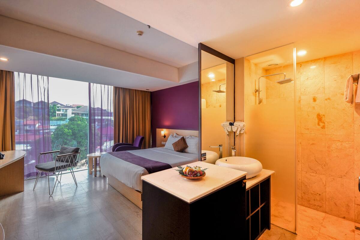 A modern hotel room with a bed, bedside table, and a shower area.