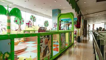 Children can play safely in this enclosed play area featuring a colorful play structure and animal-themed murals.
