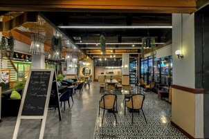 Un caffè moderno con una lavagna a menù, piante pensili e una varietà di posti a sedere.