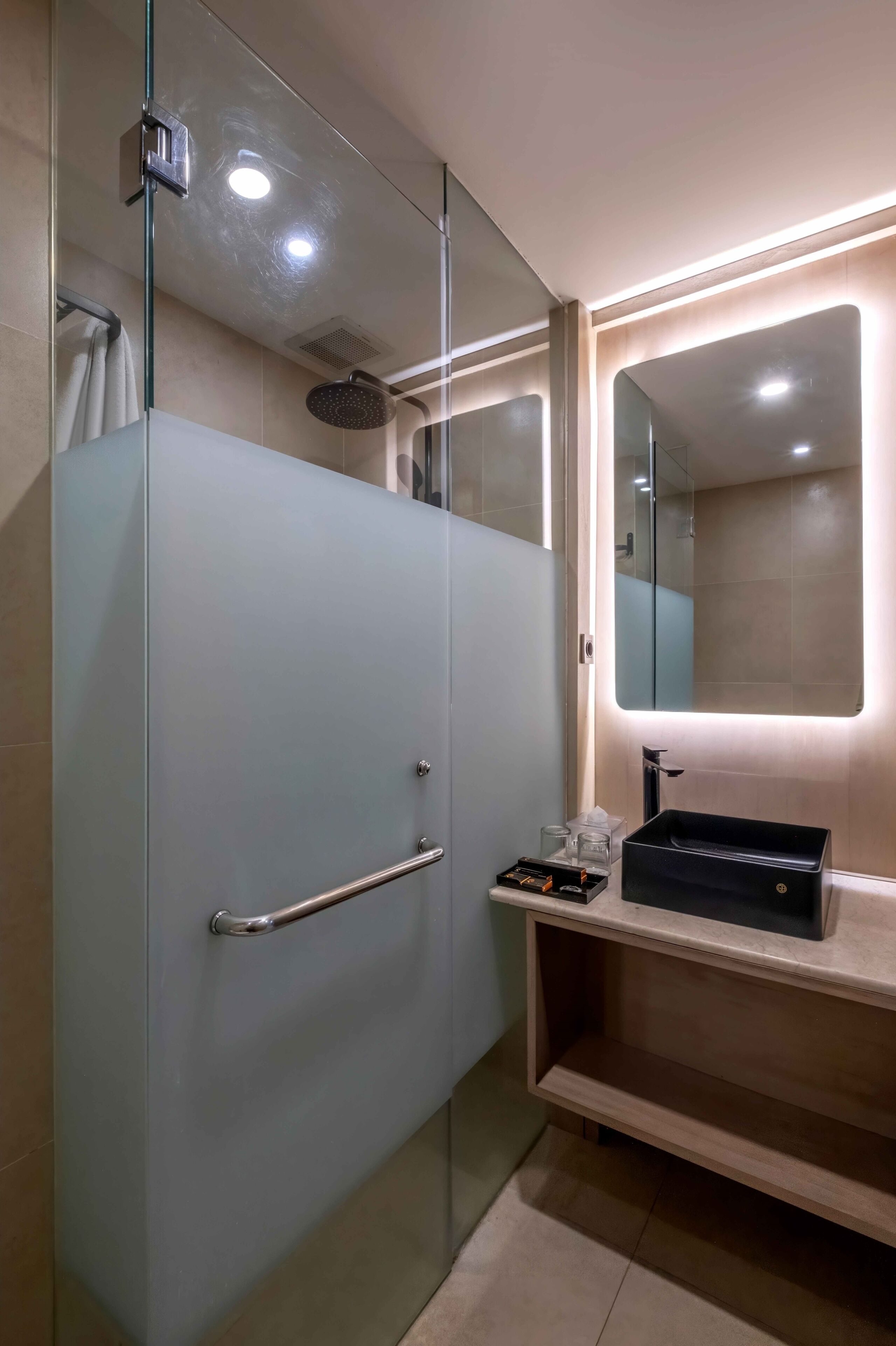 A modern bathroom with a glass shower enclosure, a vanity with a mirror, and a sink.