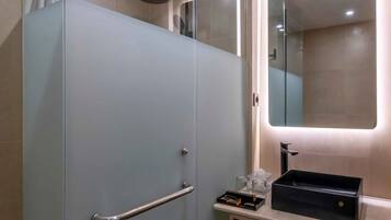 A modern bathroom with a glass shower enclosure, a vanity with a mirror, and a sink.
