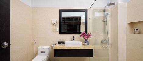 A modern bathroom with a glass-enclosed shower, a white toilet, a beige sink with a black countertop, and a mirror above the sink.