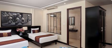 A hotel room with two beds, a large painting, a window with blinds, a bathroom, and a wardrobe.