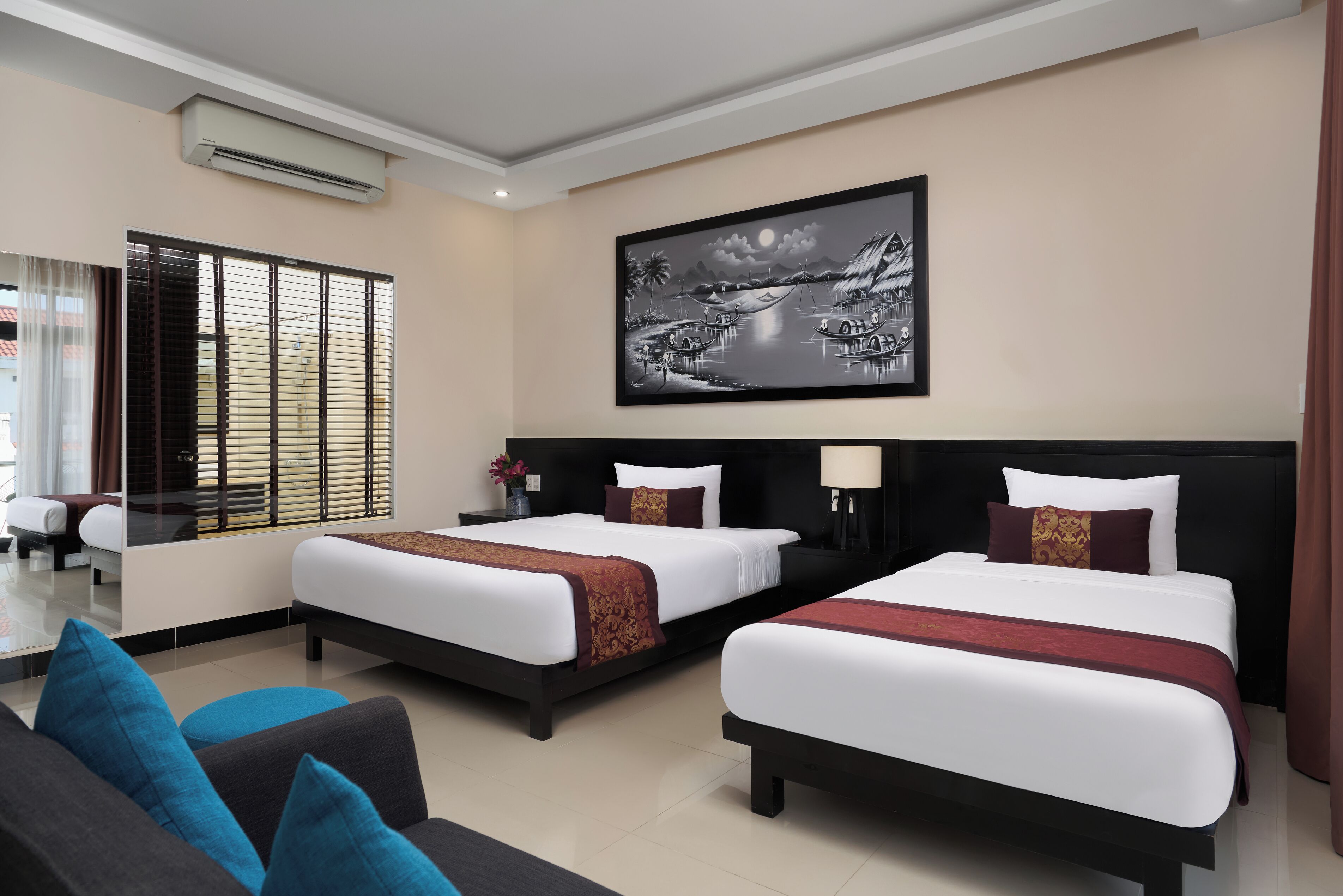 A hotel room with two beds, a sofa, and a large painting on the wall.