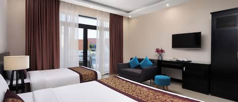 A hotel room with two beds, a desk, a TV, and a view of the outside.