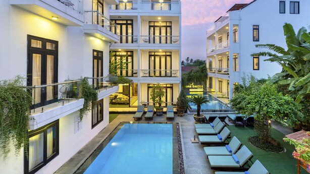 Un hôtel à plusieurs étages doté d’une piscine sur le toit, d’un espace extérieur aménagé et d’une végétation luxuriante.